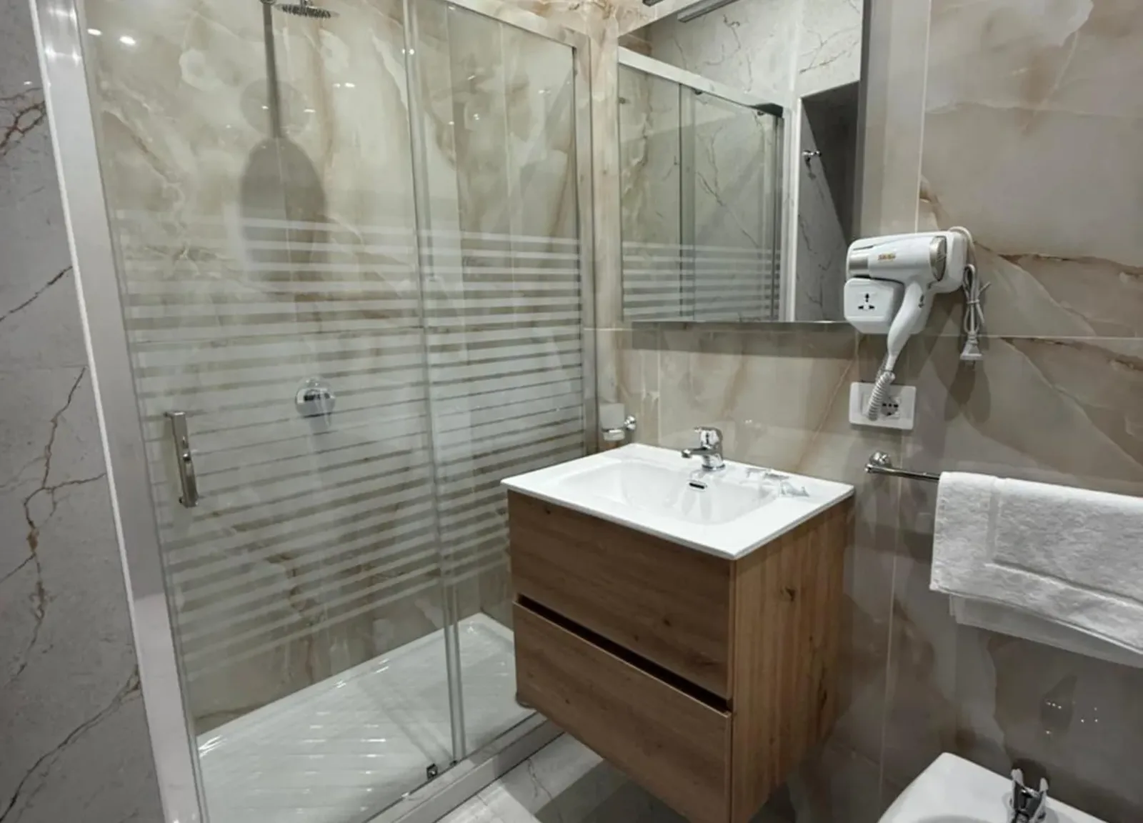 Bagno con box doccia, lavabo con mobile in legno e asciugacapelli
