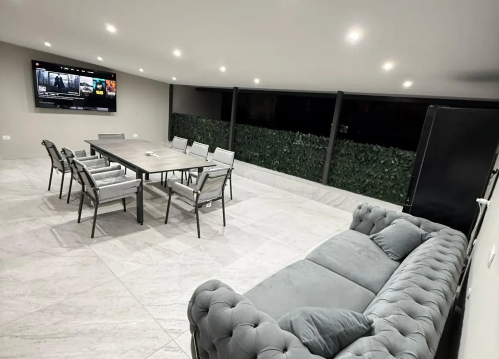 Sala comune con tavolo per otto, divano capitonné e TV grande